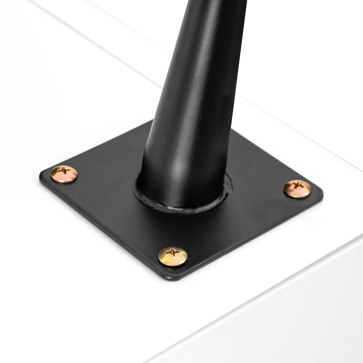 Close-up of a black steel leg base with screws attached to a white modern night stand.
