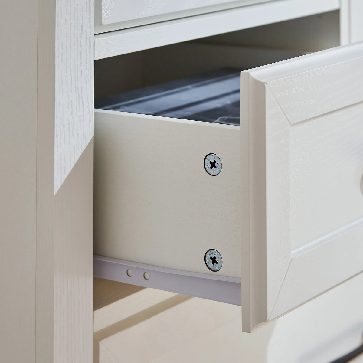 Close-up of an open white wooden drawer from an eprolo farmhouse 5 drawer dressing table.