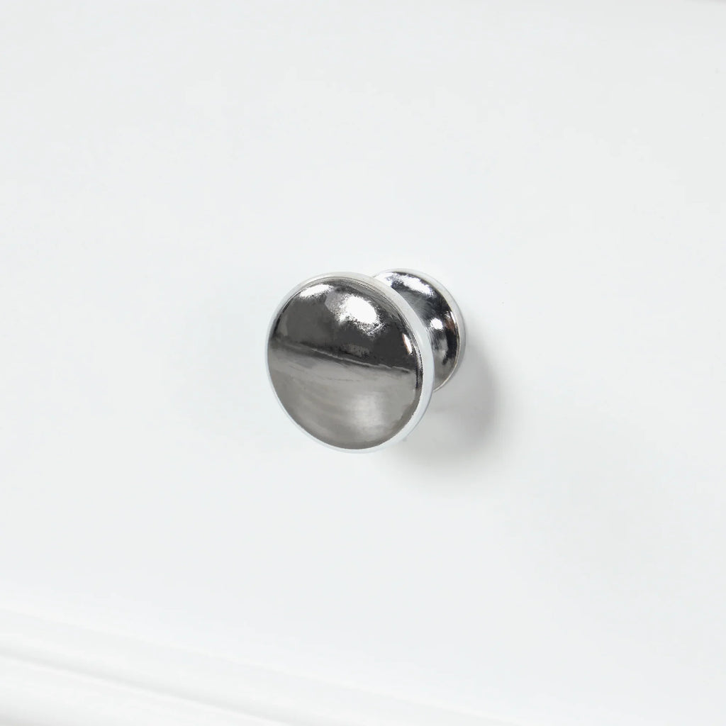 Close-up of a polished chrome knob on a white eprolo bathroom vanity drawer