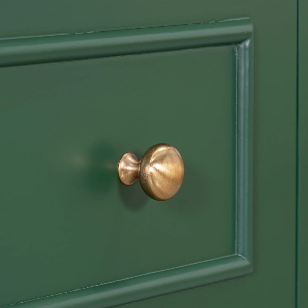 Gold round knob on a green eprolo bathroom vanity drawer with solid wood frame.
