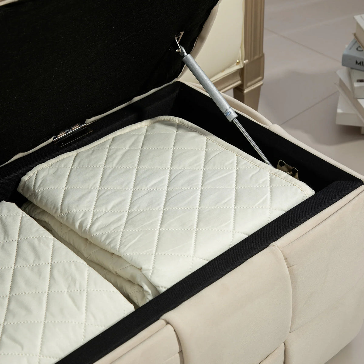 Open beige eprolo storage ottoman showing quilted fabric bedding inside with safety hinge.