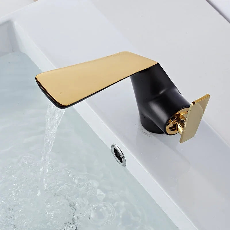 Modern black and gold copper bathroom faucet with running water in a white washbasin.