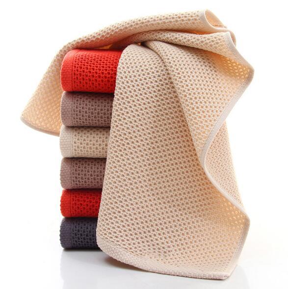 Stack of colorful eprolo waffle cotton hand towels in red, beige, and grey.