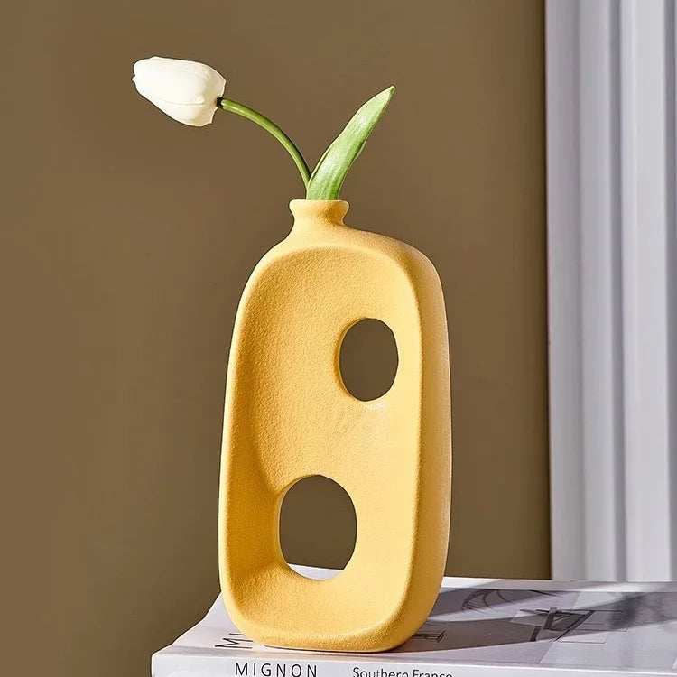 Modern yellow ceramic eprolo vase with abstract holes and a single white tulip