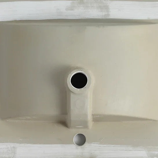 Close-up of the drain hole and underside of an eprolo white ceramic bathroom sink basin.