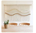 Boho macrame wall hanging tapestry with wavy patterns hanging above a wooden dining table.