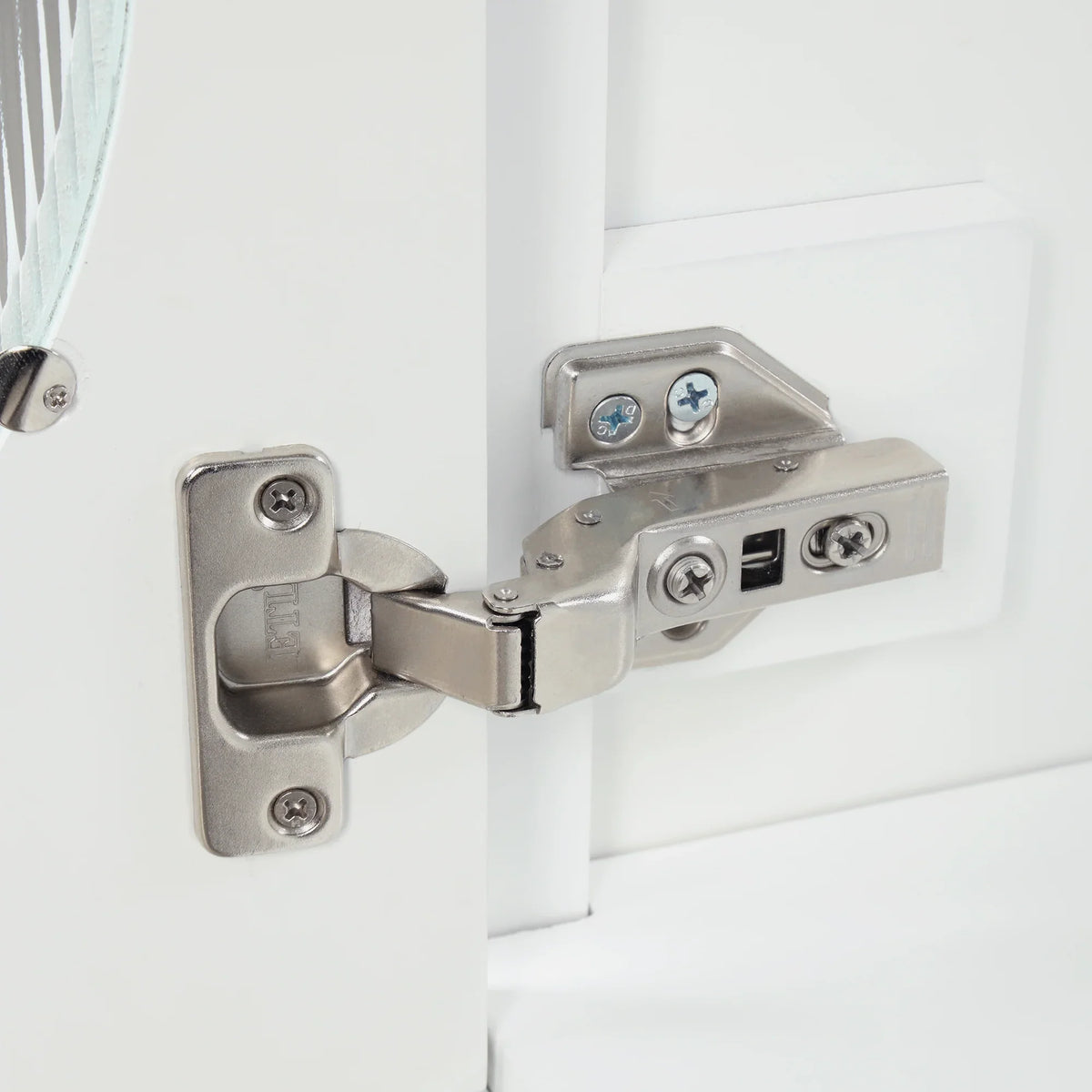 Close-up of a silver metal hinge installed on a white eprolo bathroom vanity cabinet door.