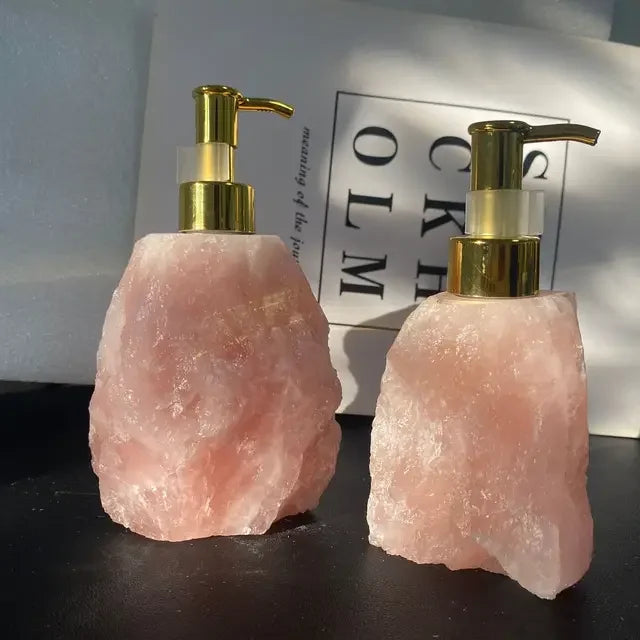 Two eprolo natural pink crystal stone liquid soap dispensers with gold pumps.