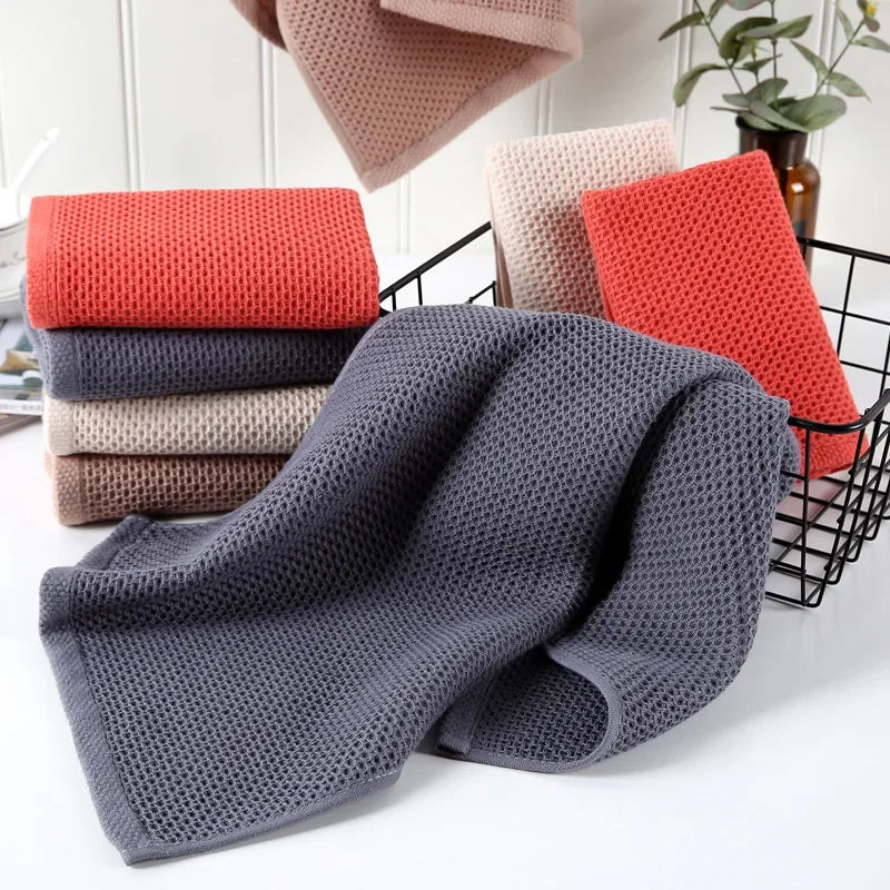 Stacked eprolo waffle weave cotton hand towels in red, grey, and beige colors.