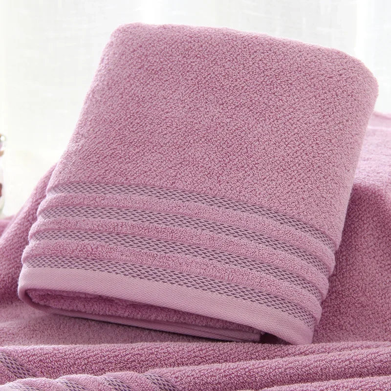 Folded purple eprolo thickened cotton bath towel with a striped textured border.