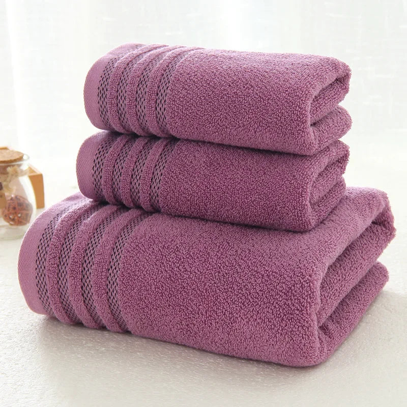 A set of three folded purple cotton bath towels by eprolo with decorative stripe textures.
